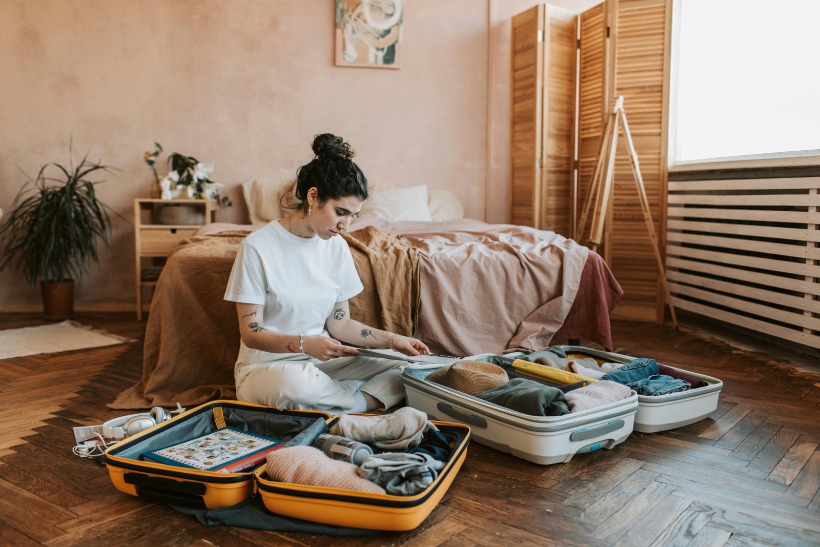 Woman confidently unpacking stylish, wrinkle-free travel clothes from her suitcase in a hotel room, illustrating stress-free packing and an effortless travel wardrobe for women.