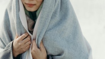 Luxury cashmere travel wrap offering comfort and style to an elegant female traveler on an airplane, showcasing its versatility as a shawl or blanket.