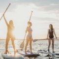 Two energetic sisters on a wellness travel adventure, actively engaged in fitness in a beautiful outdoor location, promoting healthy travel habits and well-being.