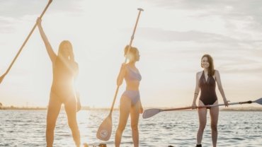 Two energetic sisters on a wellness travel adventure, actively engaged in fitness in a beautiful outdoor location, promoting healthy travel habits and well-being.
