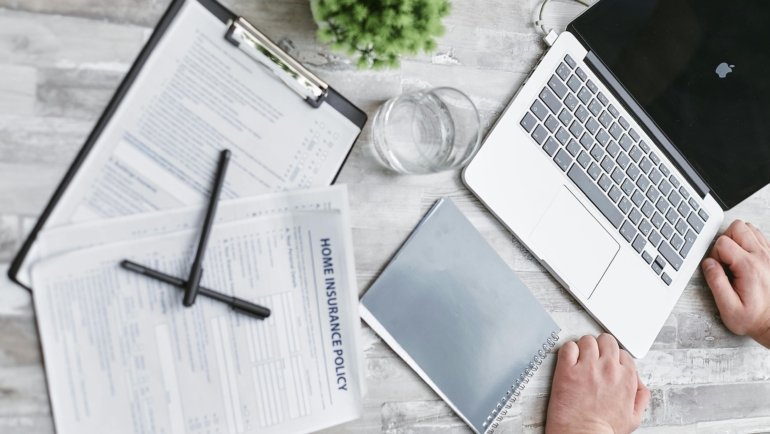 Aon travel claims guide: organized travel insurance documents, passport, and a digital claim form on a laptop, illustrating a smooth step-by-step filing process.