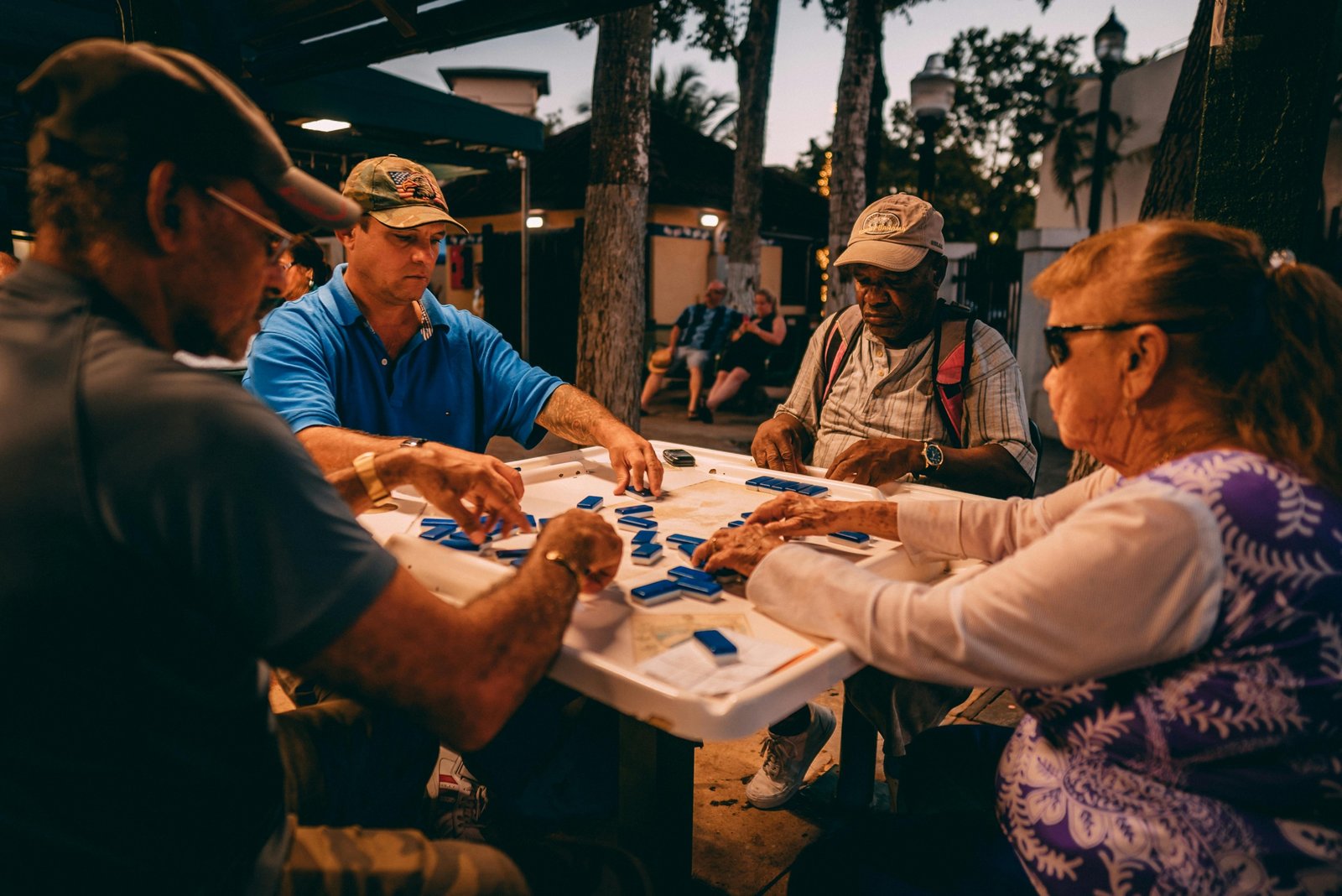 Happy friends playing with a portable travel mahjong set on a sunny outdoor vacation, highlighting its compact design and social enjoyment.