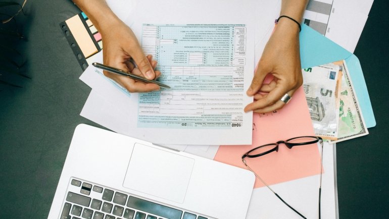 Person meticulously organizing business travel receipts and expense reports for a smooth travel fee settlement and reimbursement process.
