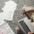 Best day to book air travel to save money on flights, with a person planning their trip on a laptop and calendar.