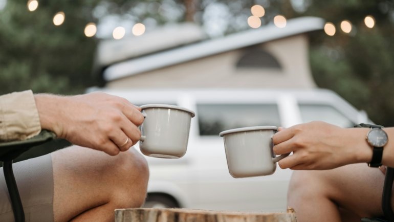 Compact wooden travel cribbage board set up in a cozy cafe, with two travelers playing and enjoying a game, illustrating portable entertainment and social interaction on the go.