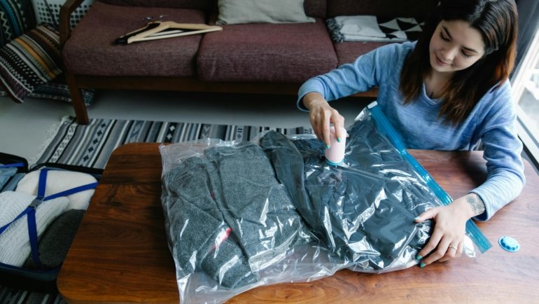 Vacuum travel bags with hand pump compressing clothes for efficient, space-saving travel packing and suitcase organization.