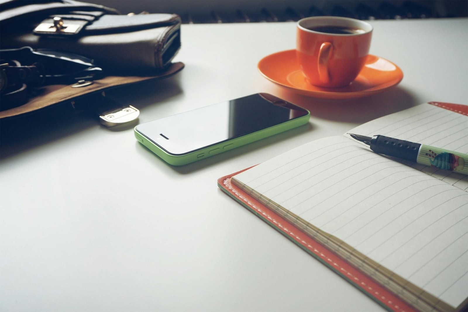 A hands-on view of an open leather Midori Traveler's Notebook with a pen, ready for personalized journaling and adventure planning, surrounded by travel maps and a hot beverage.