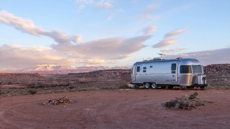 Modern travel trailer boondocking in a serene natural landscape, powered by a high-performance deep-cycle battery (lithium or AGM) for off-grid RV camping and stress-free adventures.