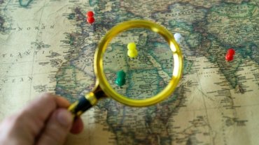 Person planning an affordable global adventure using Gate 1 Travel special deals for escorted tours and vacation packages, with a world map visible.