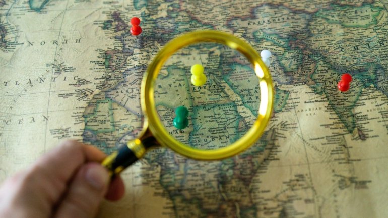 Person planning an affordable global adventure using Gate 1 Travel special deals for escorted tours and vacation packages, with a world map visible.