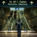 A person confidently carrying the tomtoc travel backpack 40l, a sleek and durable carry-on bag, through a bright, modern airport terminal, symbolizing efficient and organized travel.