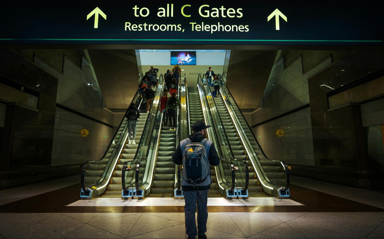 A person confidently carrying the tomtoc travel backpack 40l, a sleek and durable carry-on bag, through a bright, modern airport terminal, symbolizing efficient and organized travel.