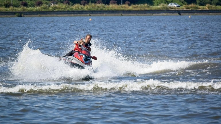 A rider expertly steers a personal watercraft (PWC) through a dynamic turn on the water, demonstrating precise control, throttle application, and body lean crucial for safe navigation.