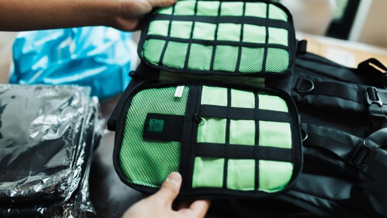 Traveler's hands neatly packing a suitcase with colorful compression cubes, demonstrating efficient space-saving and organization for stress-free travel.