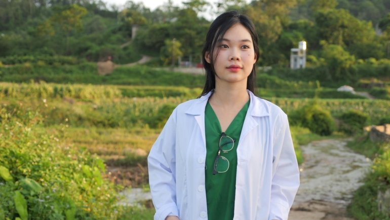 A smiling Nurse Practitioner in scrubs with a stethoscope, looking confidently towards a horizon featuring both urban and natural elements, symbolizing the professional growth and travel opportunities of NP assignments.