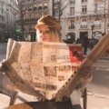A smiling traveler planning their Paris adventure with a classic paper travel map at a charming Parisian cafe, symbolizing confident navigation and discovery in the City of Light.