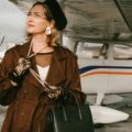 Stylish traveler with a luxury Dior-style travel bag at a modern airport, representing sophisticated journeys and premium luggage.
