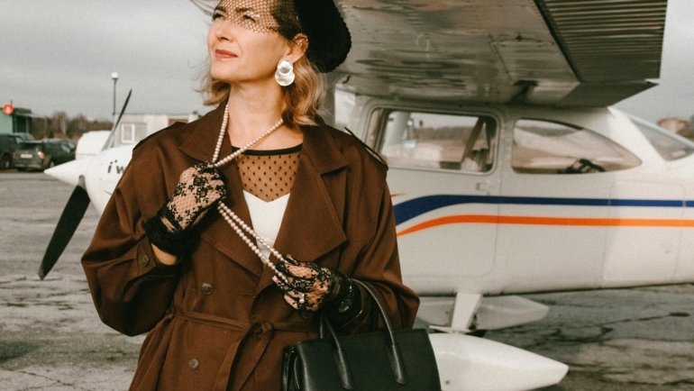 Stylish traveler with a luxury Dior-style travel bag at a modern airport, representing sophisticated journeys and premium luggage.