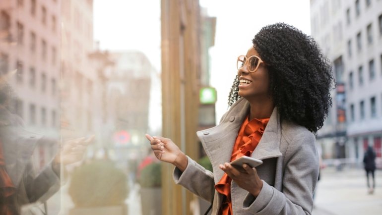Black traveler confidently using the Martinique Lewis ABC Travel Green Book app on a smartphone to discover safe, inclusive, and welcoming travel experiences with a global community.