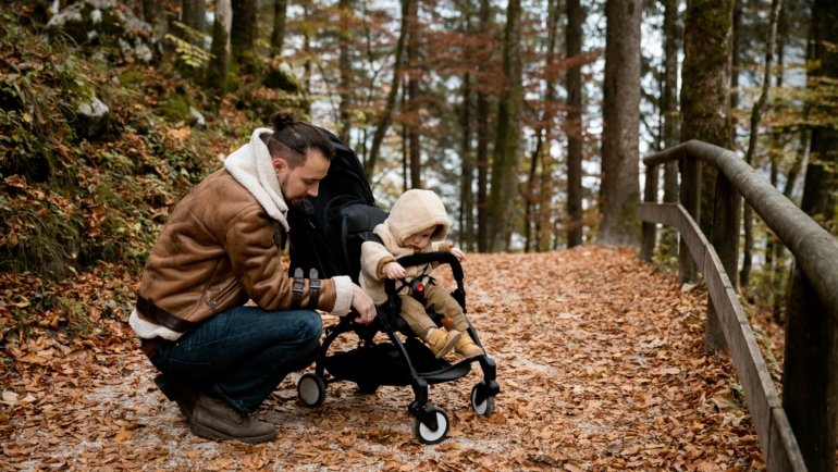 A smiling family of four, with parents easily pushing their two young children in a compact, lightweight double stroller through a bright airport terminal, representing the best double stroller for travel.
