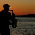 Musician happily playing a portable travel saxophone in a beautiful outdoor landscape, emphasizing freedom and convenient music practice while traveling.