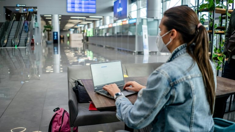 Diverse business professional working on a laptop in a modern airport lounge, symbolizing efficient BT travel, global connectivity, and successful corporate productivity.