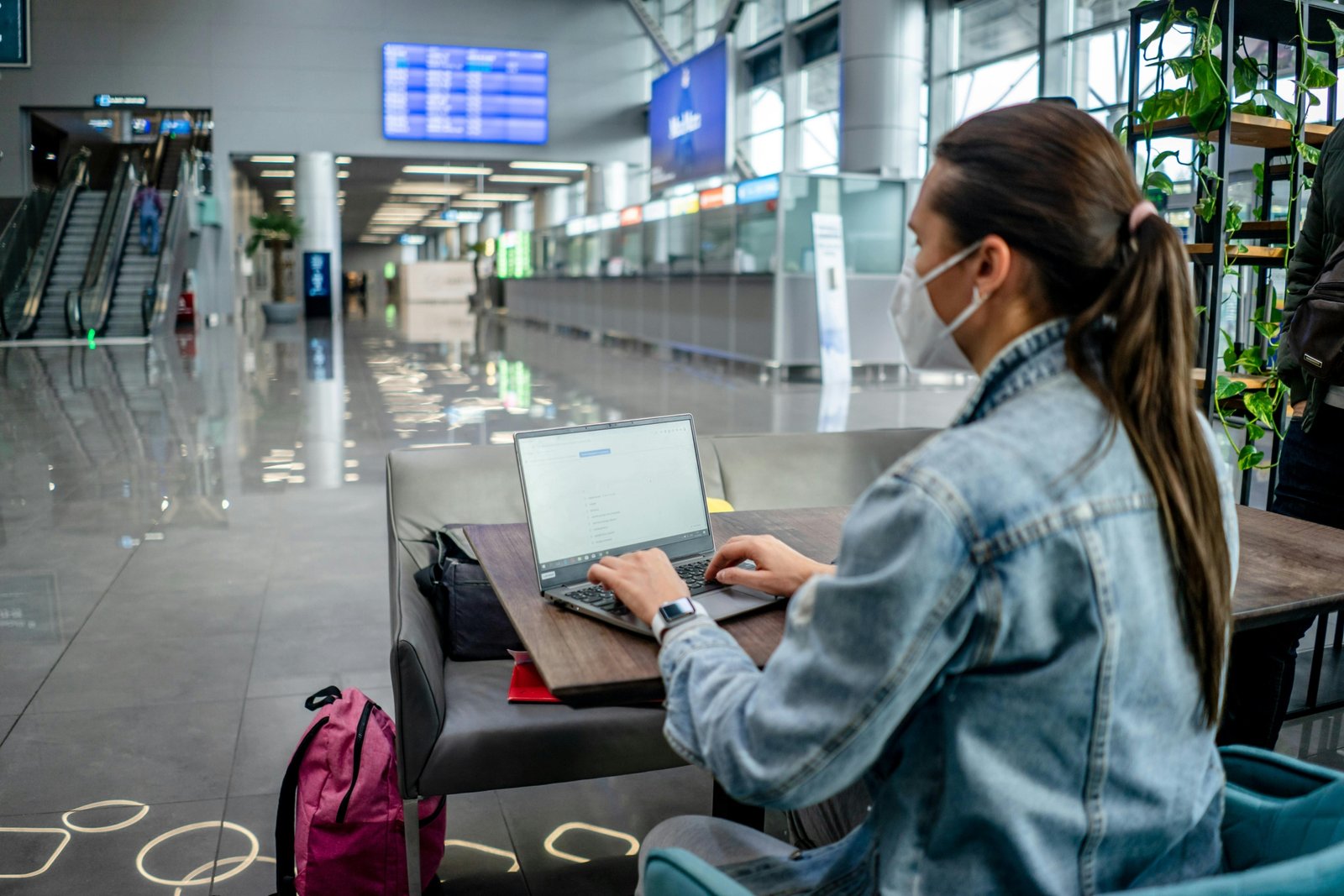 Diverse business professional working on a laptop in a modern airport lounge, symbolizing efficient BT travel, global connectivity, and successful corporate productivity.