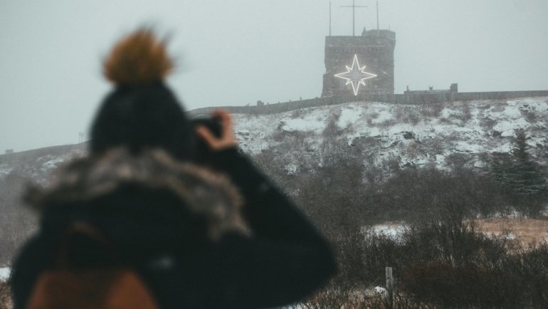Happy traveler capturing a stunning vacation photo with a compact digital camera, illustrating the best compact camera for travel for superior image quality and portability.
