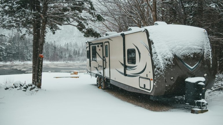 High-quality, multi-layered travel trailer cover securely protecting an RV from snow and harsh winter elements, emphasizing essential winter storage and investment protection.