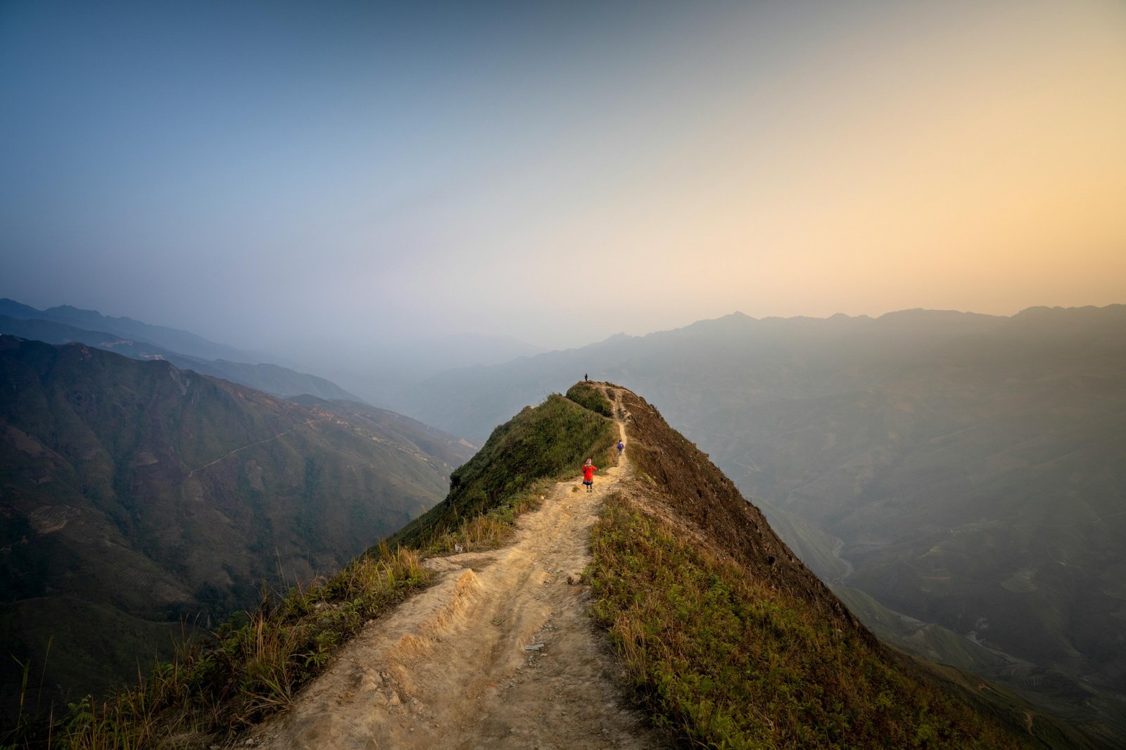 Lone traveler walking on a winding path through a vast, beautiful mountain landscape, symbolizing an inspiring journey of discovery, adventure, and personal growth, ideal for wanderlust and travel quotes.