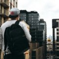 A modern traveler, casually walking with a versatile carry-on travel pack (similar to Osprey Porter 46) through a city street or airport, embodying efficient one-bag travel for digital nomads and weekend adventurers.