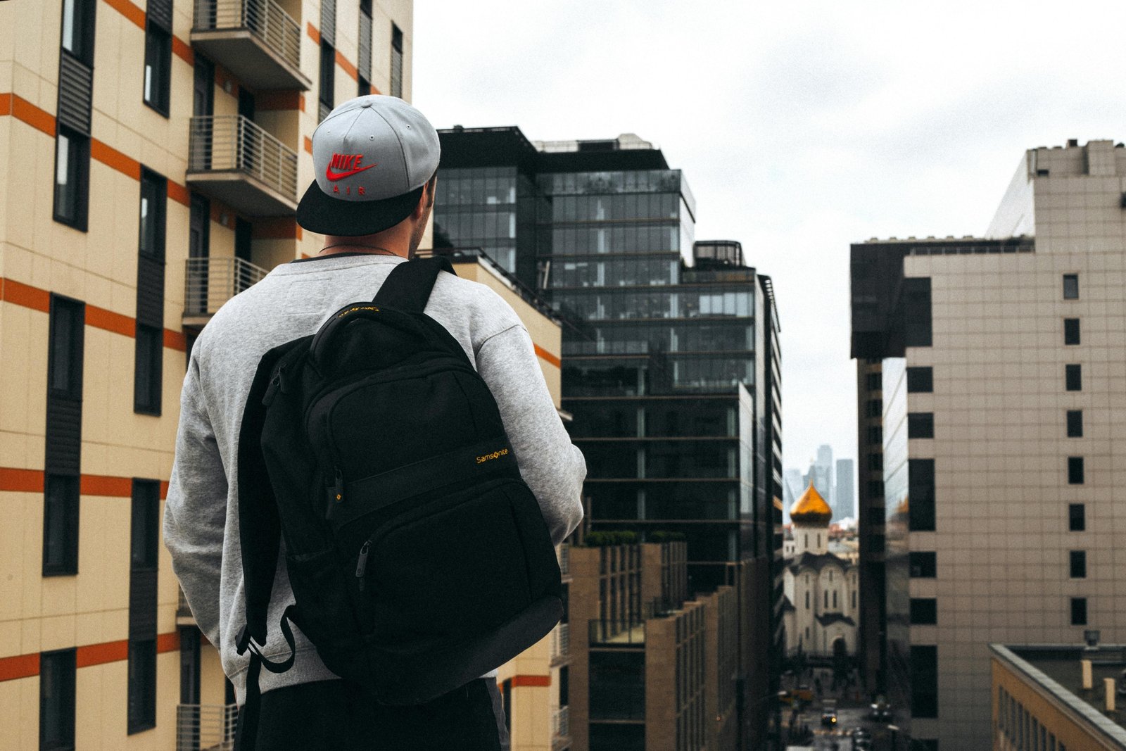 A modern traveler, casually walking with a versatile carry-on travel pack (similar to Osprey Porter 46) through a city street or airport, embodying efficient one-bag travel for digital nomads and weekend adventurers.