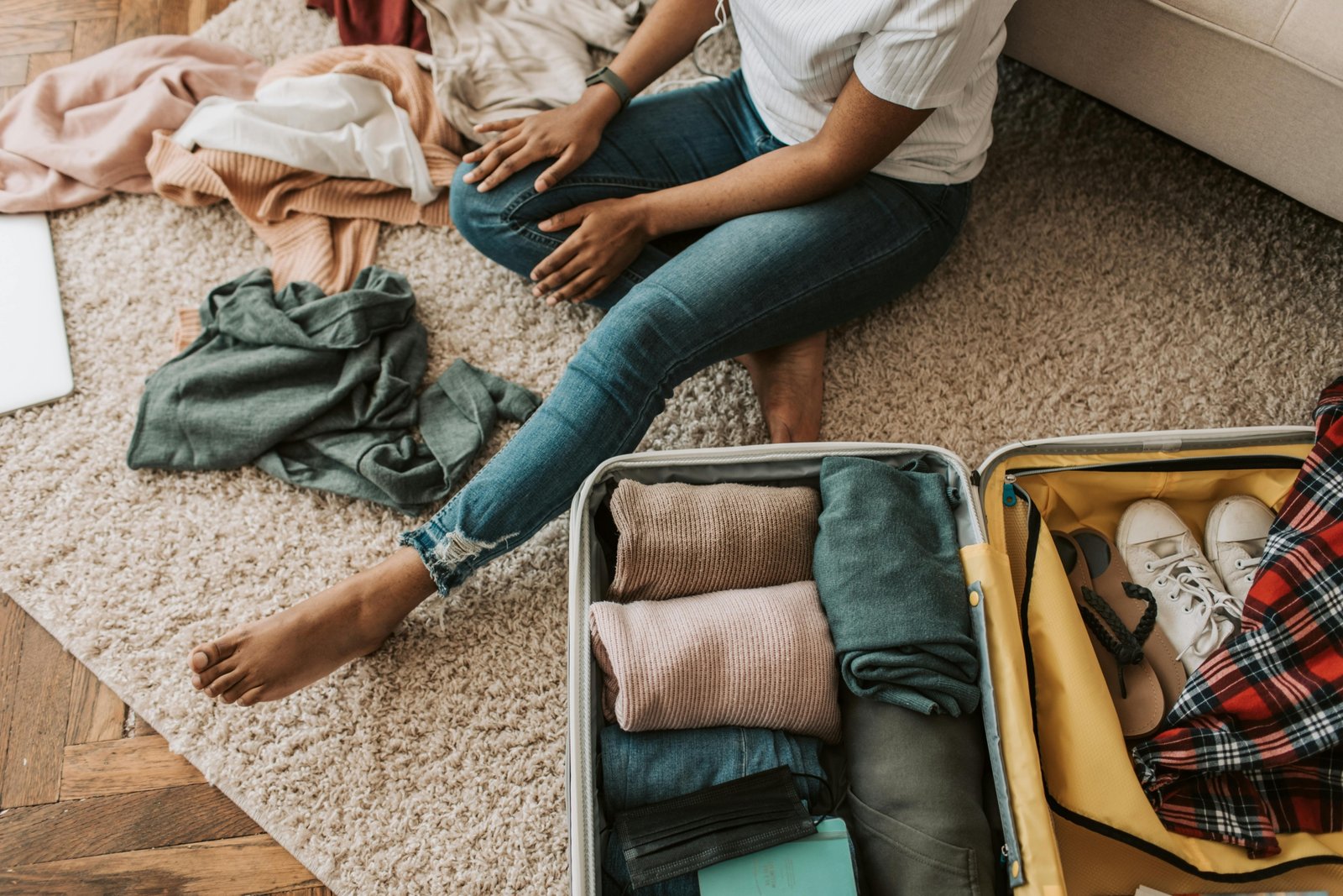 Person comically struggling to close an overstuffed suitcase with clothes spilling out, illustrating the relatable humor of traveller memes and common packing challenges before a trip.