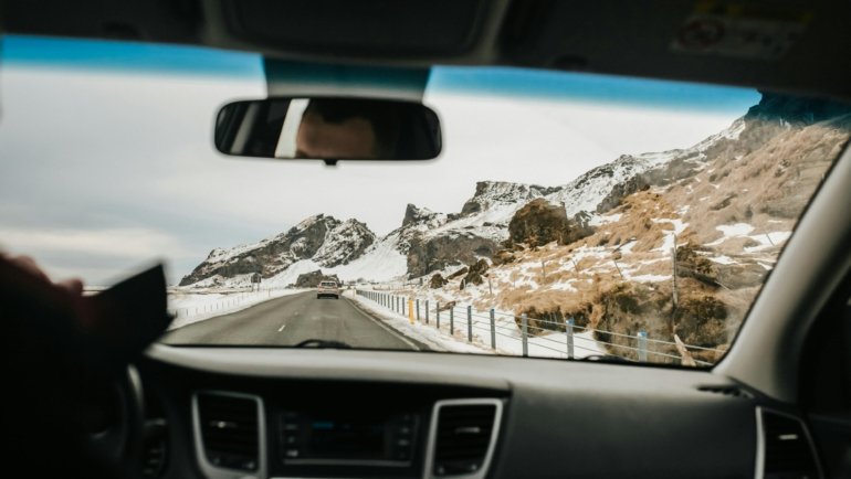 Vehicle driving on snowy Pennsylvania highway, illustrating winter travel restrictions and safe driving conditions advised by PennDOT.