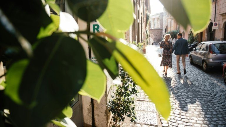 A person easily rolls a lightweight carry-on spinner suitcase or carries a travel backpack through a charming European cobblestone street, illustrating the best luggage choices for European travel, train trips, and efficient city exploration.