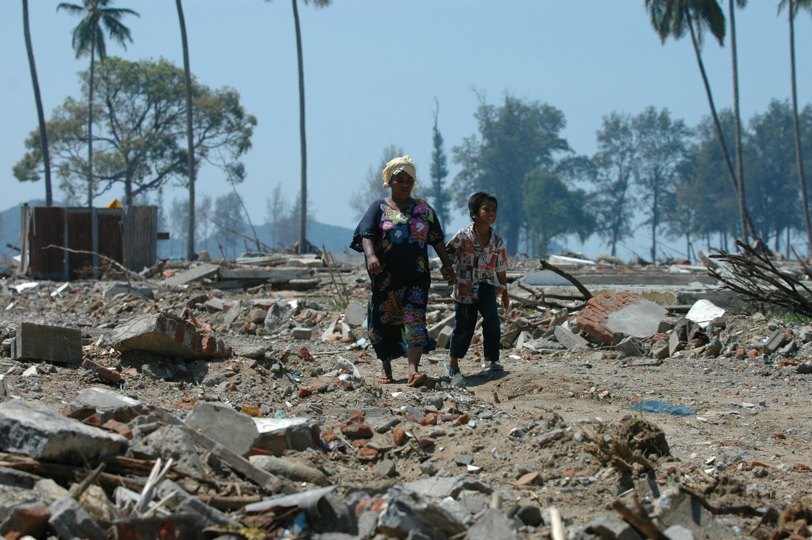 An aerial wide-angle shot of a massive tsunami's aftermath, showing debris and water inundation stretching far inland from the original coastline, highlighting the extensive reach of these powerful waves.