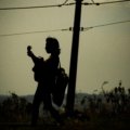 Musician playing a portable electric travel guitar, showcasing the convenience and inspiration for creating music while exploring new destinations.