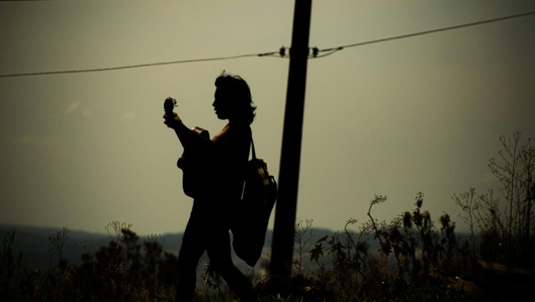 Musician playing a portable electric travel guitar, showcasing the convenience and inspiration for creating music while exploring new destinations.
