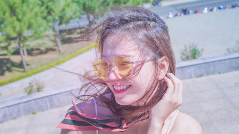 Happy woman applying travel size hair styling mousse for effortless, perfect hair while traveling, ideal for carry-on and all hair types.
