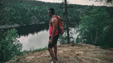 A solo traveler with a light backpack stands on a scenic overlook, symbolizing the freedom and thrill of finding last-minute deals for spontaneous solo travel adventures.