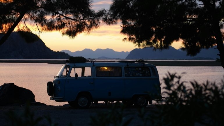Blue specialized RV drinking water hose securely connected to a travel trailer at a sunny campsite, ensuring safe and clean fresh water for camping and road trips.