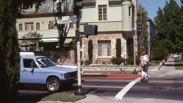 Happy parent smoothly pushing a Britax Willow Brook travel system, featuring an infant car seat attached to a lightweight stroller, demonstrating convenience and safety for city strolls with a newborn.