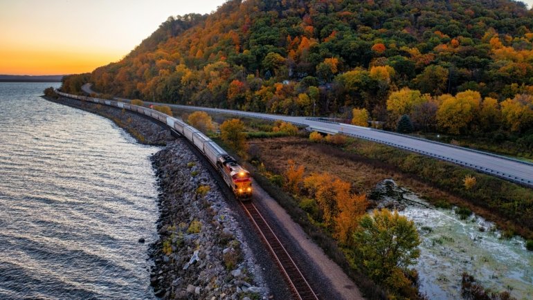 Scenic view of a Minnesota lake surrounded by colorful autumn trees, highlighting the state's diverse natural beauty and ideal outdoor adventure travel destinations.