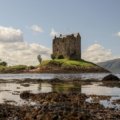 Scenic view of a historic castle ruin overlooking a lush green landscape in Ireland or Scotland, representing the best time to travel for stunning views, mild weather, and avoiding crowds.