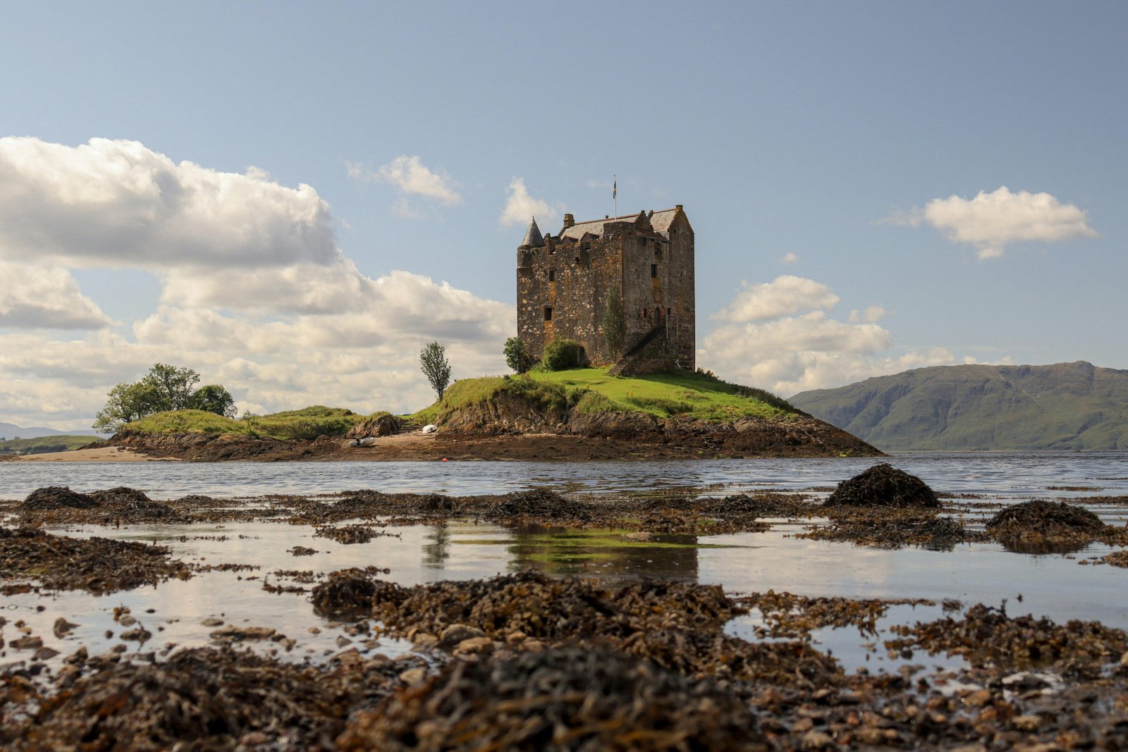 Scenic view of a historic castle ruin overlooking a lush green landscape in Ireland or Scotland, representing the best time to travel for stunning views, mild weather, and avoiding crowds.