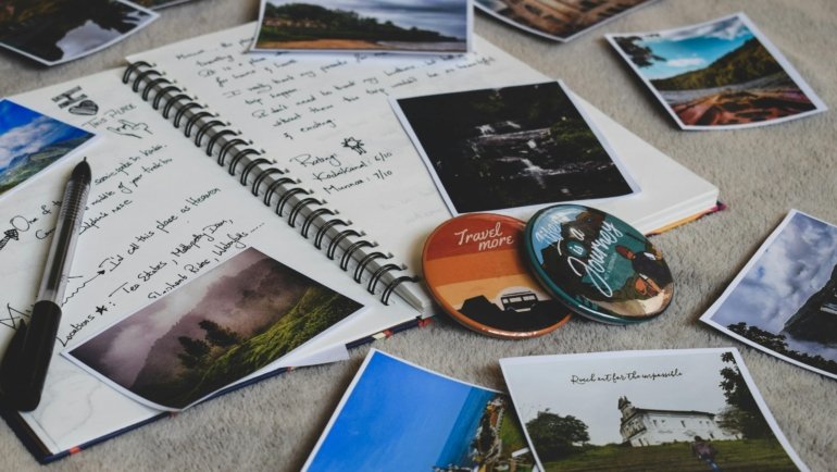 Open creative travel journal filled with sketches, handwritten notes, and collaged travel mementos like maps and tickets, alongside pens and art supplies, illustrating inspiring travel journal ideas.