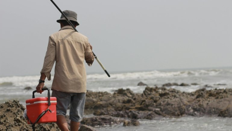 Portable travel surf rod casting on a remote beach, showcasing an angler enjoying adventure fishing with a multi-piece fishing rod designed for easy transport and saltwater fishing.