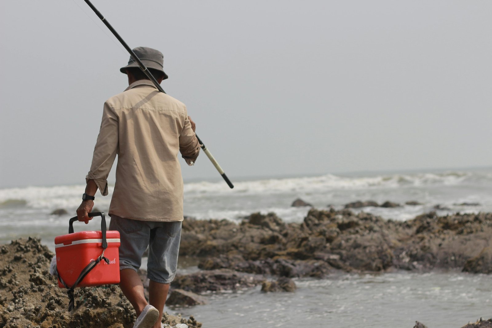 Portable travel surf rod casting on a remote beach, showcasing an angler enjoying adventure fishing with a multi-piece fishing rod designed for easy transport and saltwater fishing.