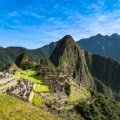 Iconic panoramic view of the ancient Inca citadel of Machu Picchu in Peru, nestled among lush green mountains under a clear, bright blue sky, illustrating the best time to visit.