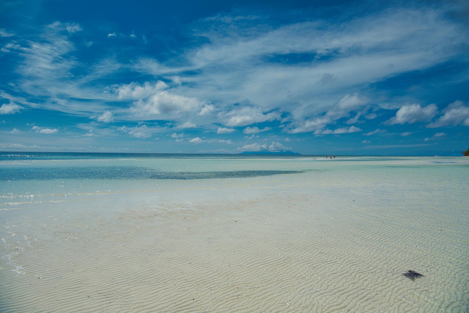 Person relaxing on a beautiful tropical beach with white sand and clear turquoise water under a sunny sky, ideal for a warm November travel escape or sunny getaway.